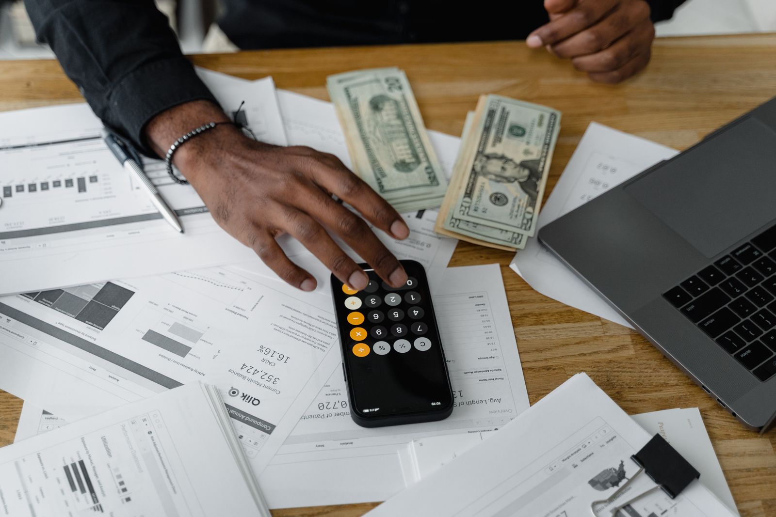 An overhead view of a calculator, cash, and paperwork laid out for financial planning