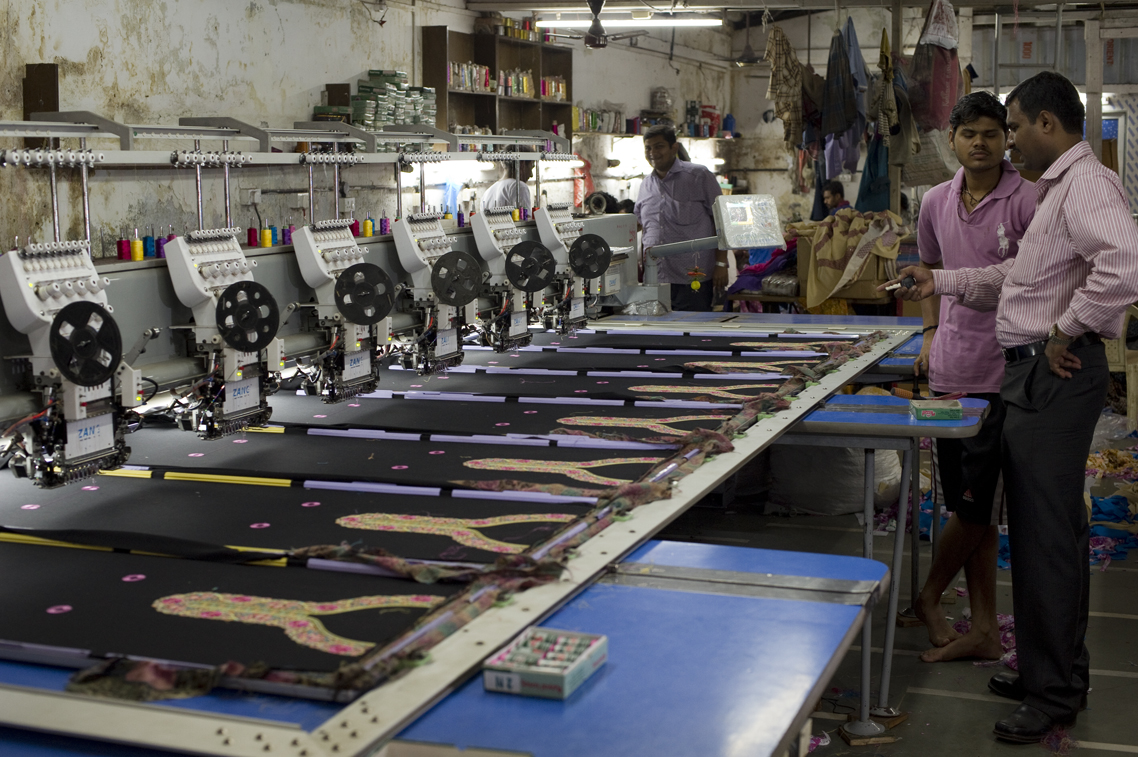 A commercial embroidery workshop with an operator running production equipment