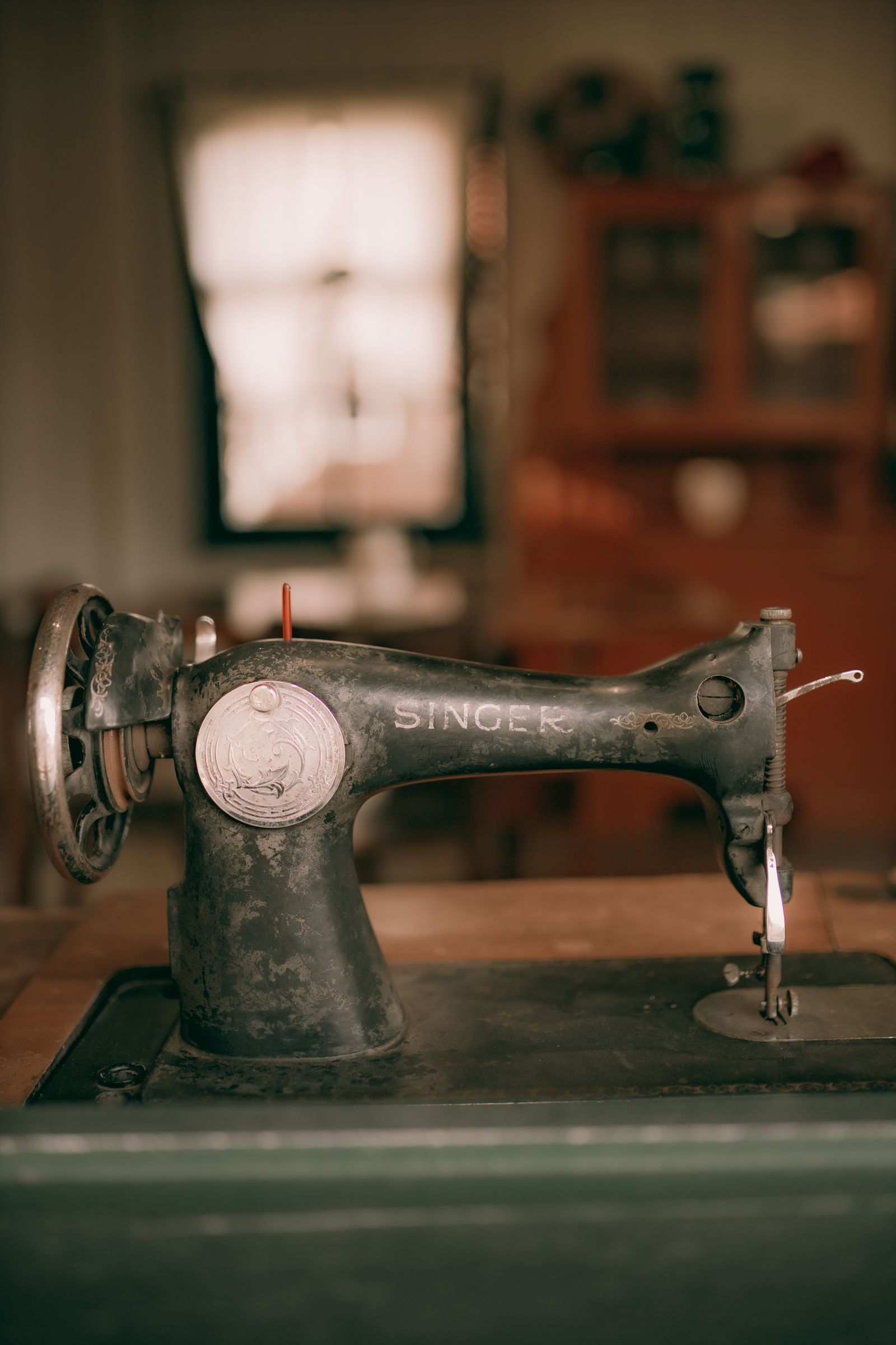 An antique sewing machine with wooden base and metal components on a vintage surface