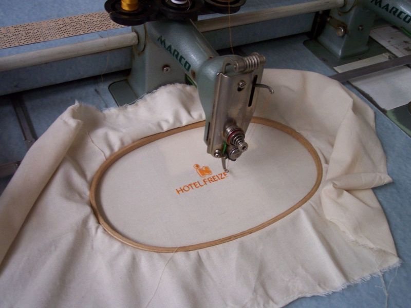 A historical industrial embroidery machine showing mechanical arms and thread guides