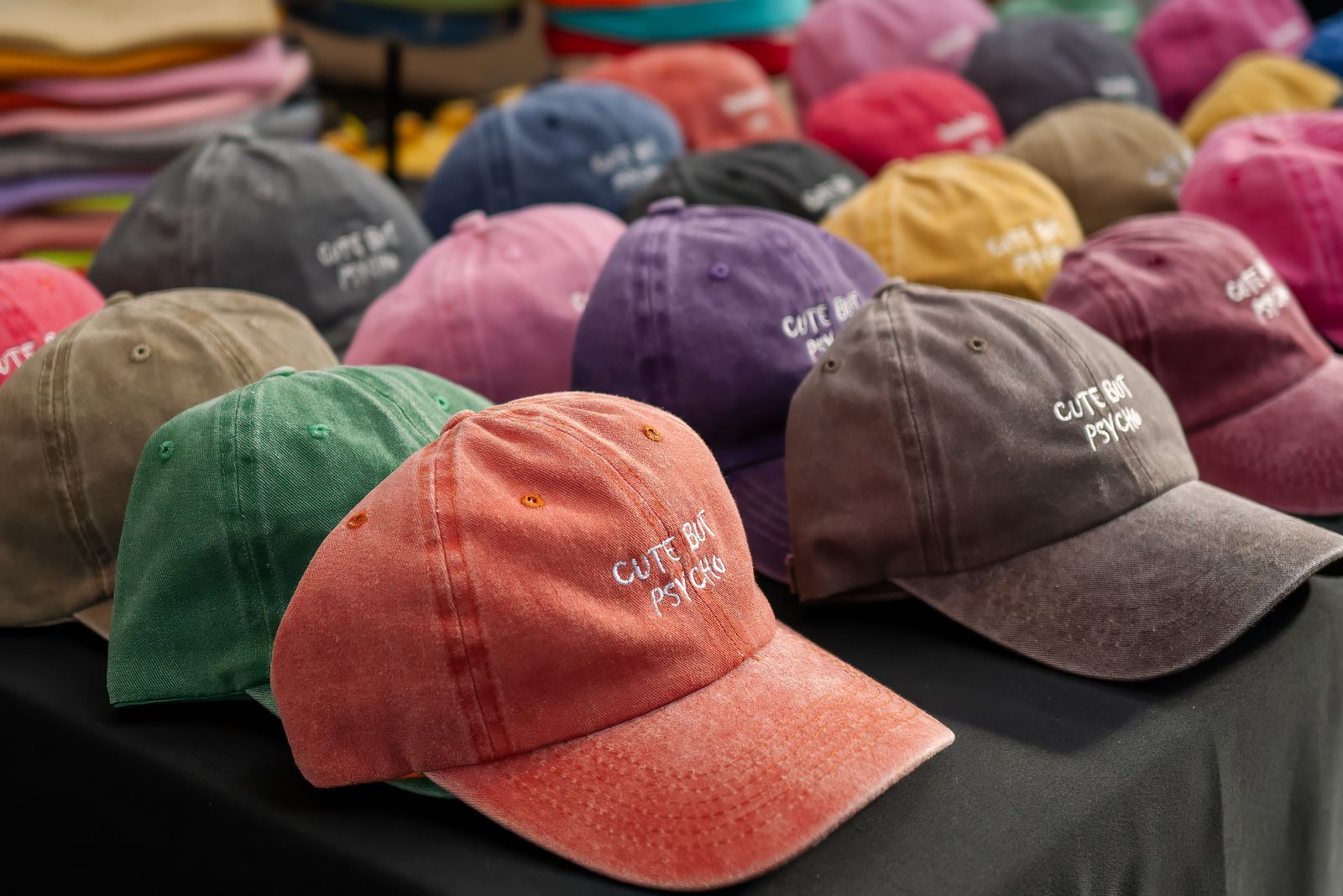 A collection of embroidered baseball caps displayed on a wooden surface