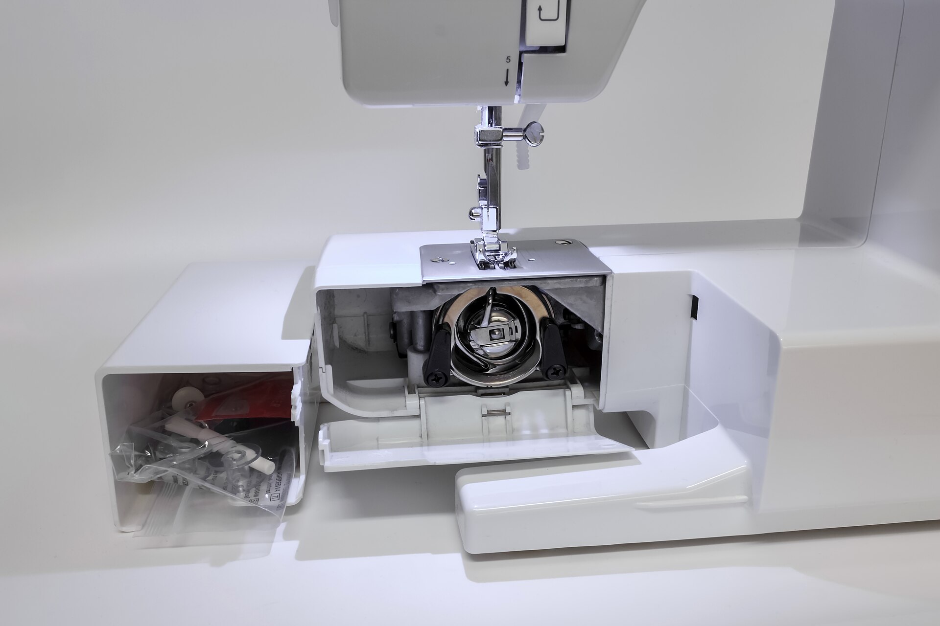 The bobbin case area of a sewing machine, opened for cleaning