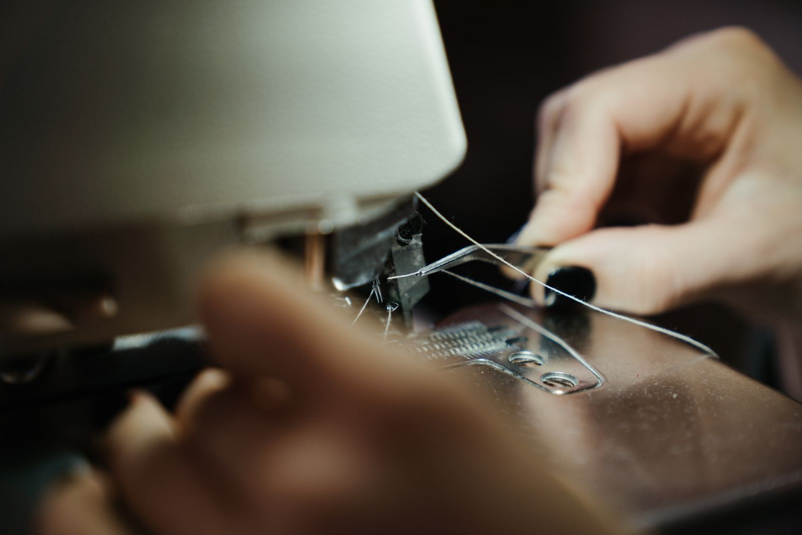 Hands at a home sewing machine workspace guiding fabric through the needle area with both hands free