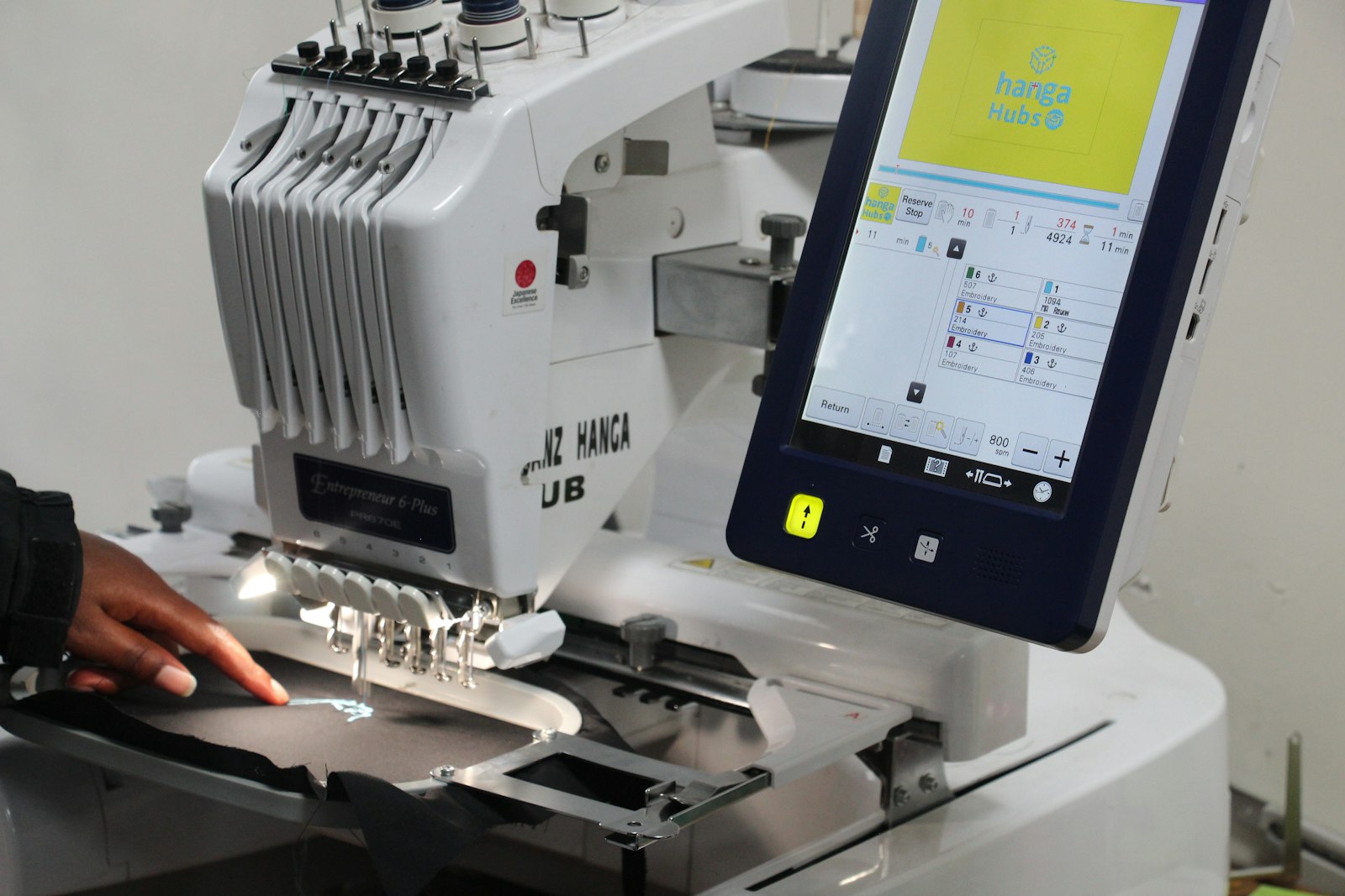 A person operating a sewing machine guiding fabric with focused hand movements