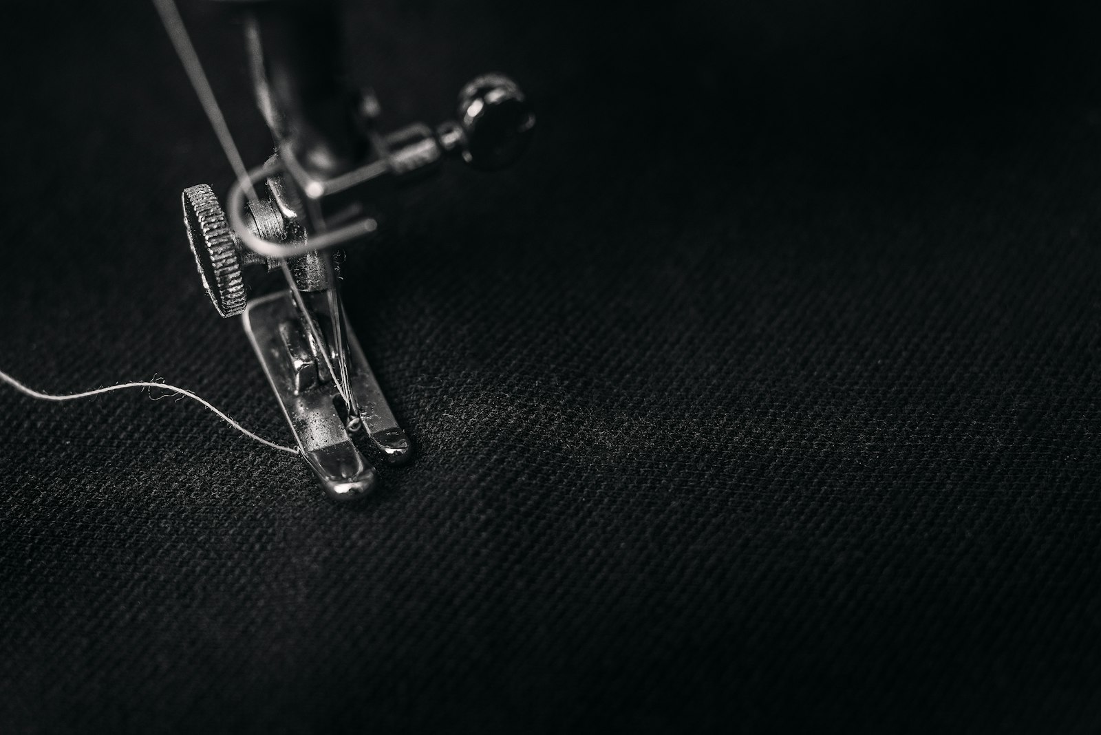 Close-up of a sewing machine presser foot at the needle plate showing the presser foot mechanism from the side