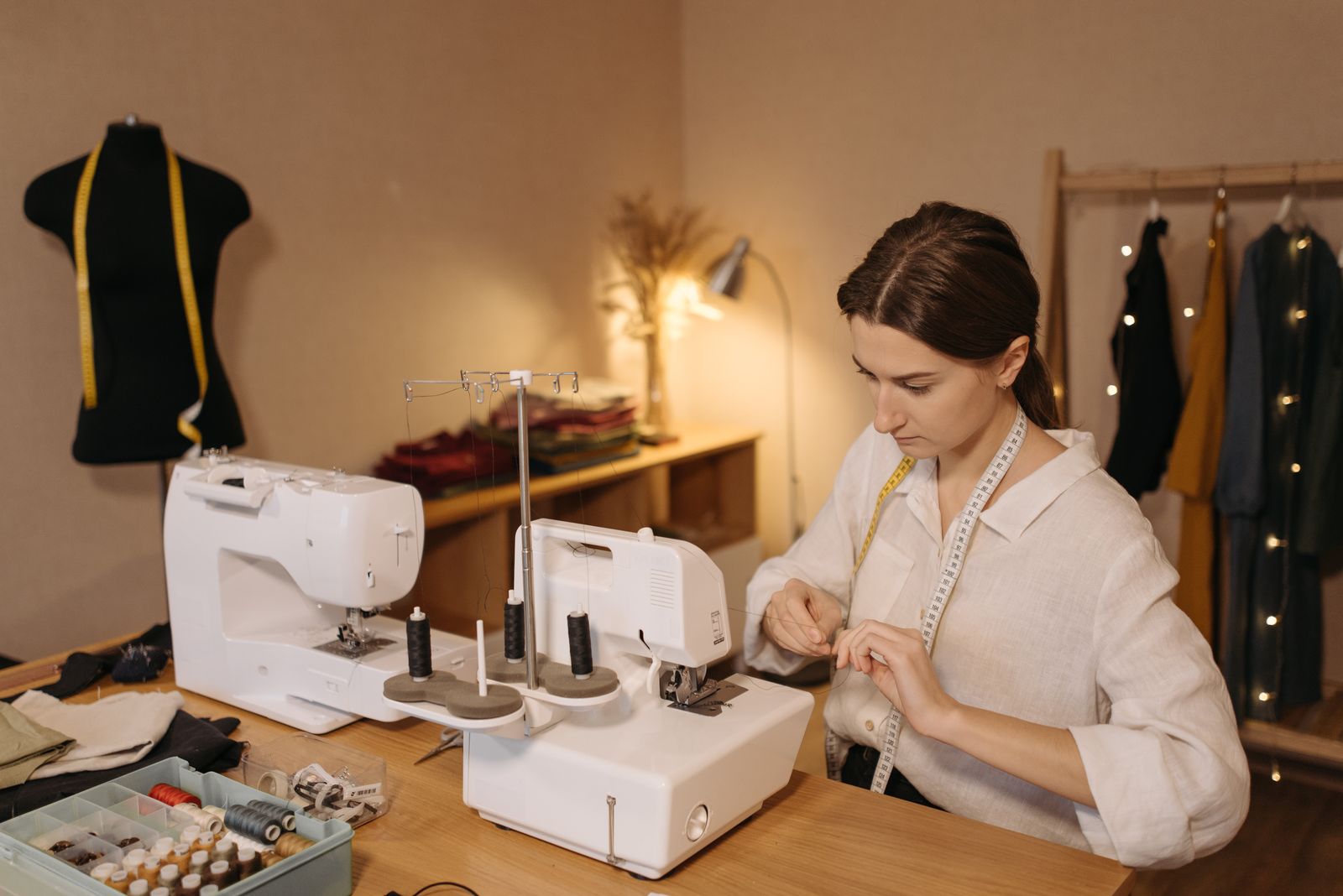 Close-up of hands threading an embroidery machine needle in a workshop