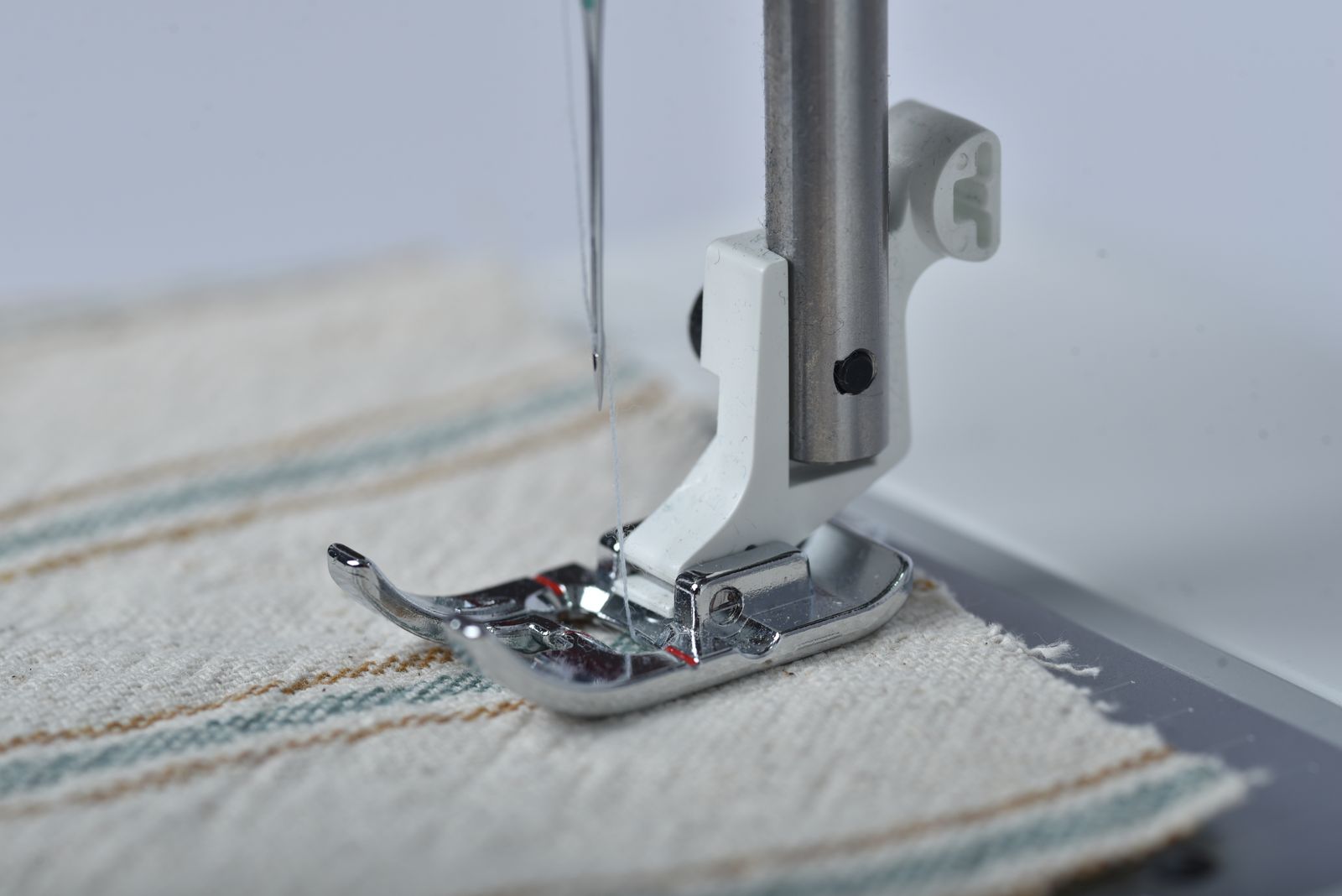 Close-up of a sewing machine needle stitching through layered fabric