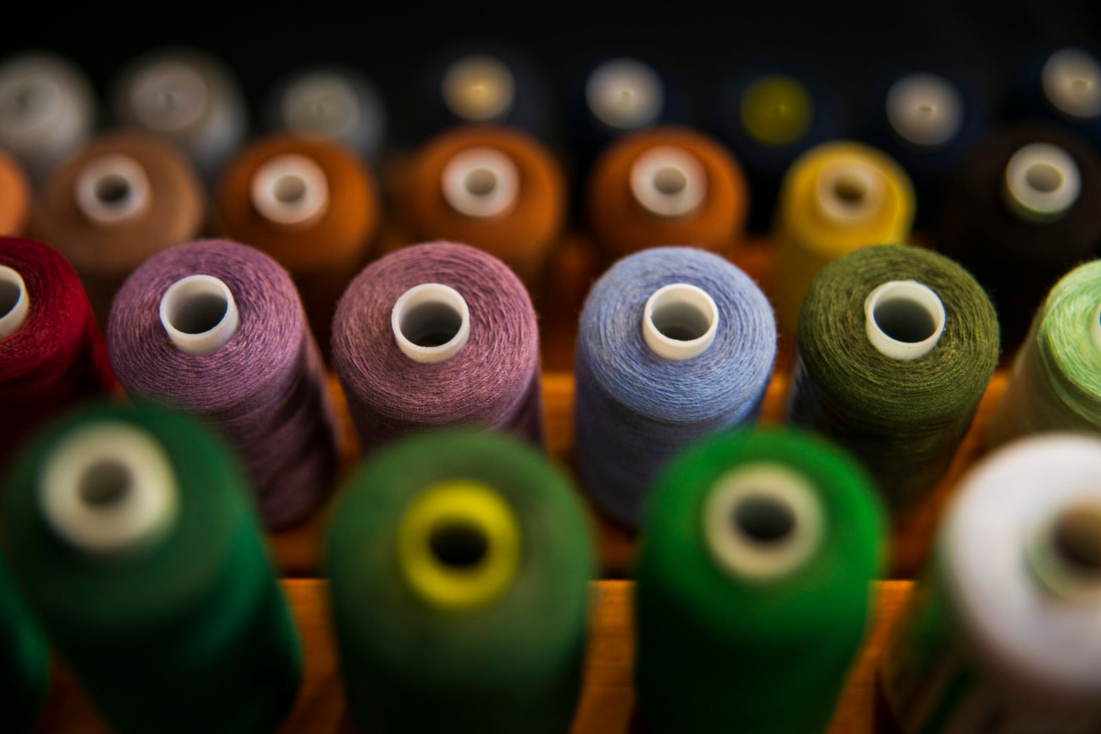Rows of colorful thread spools arranged by color in selective focus
