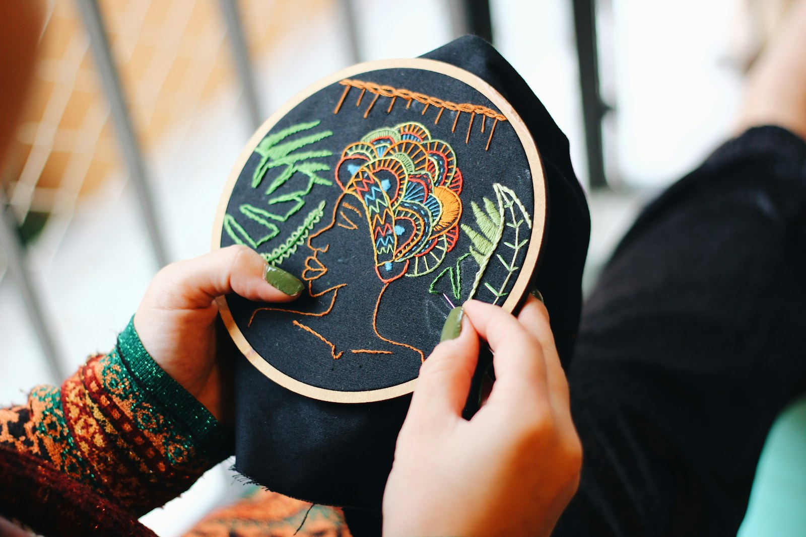 A hand-held embroidered ornament showing detailed blue and white stitching