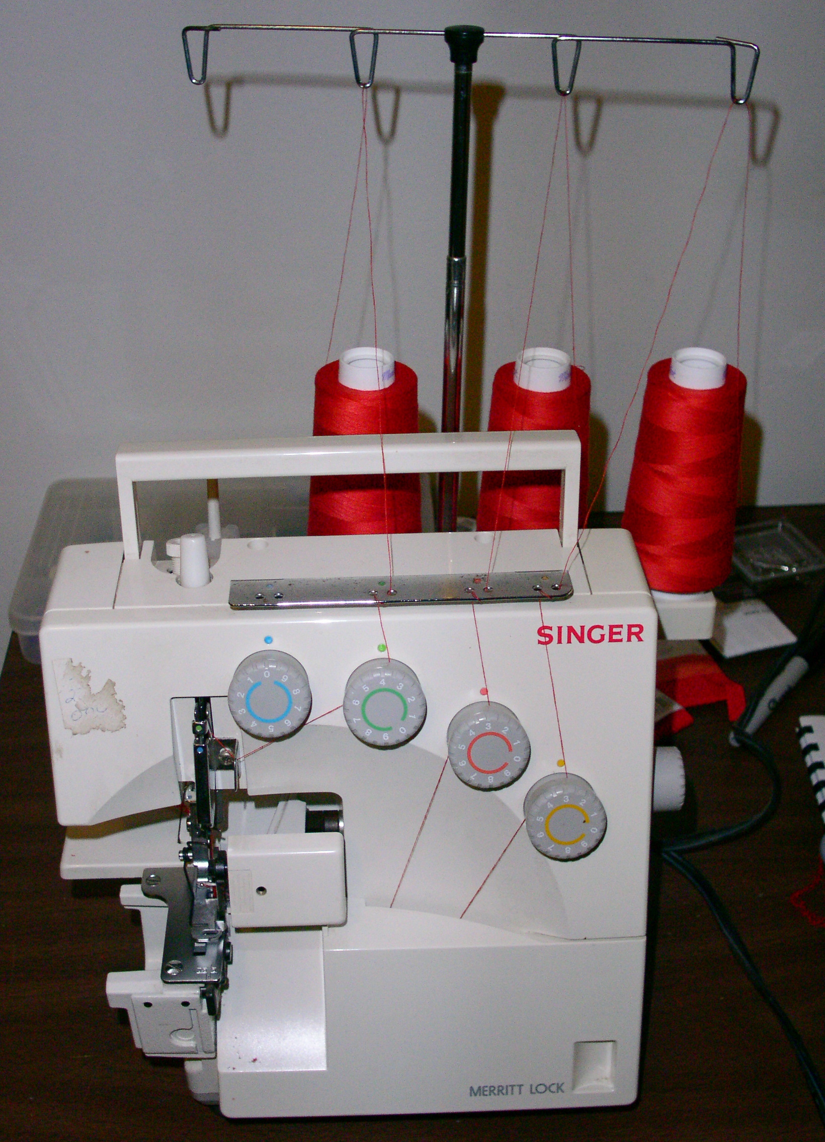 Home sewing machine in operation with fabric feeding through the presser foot area from the right side