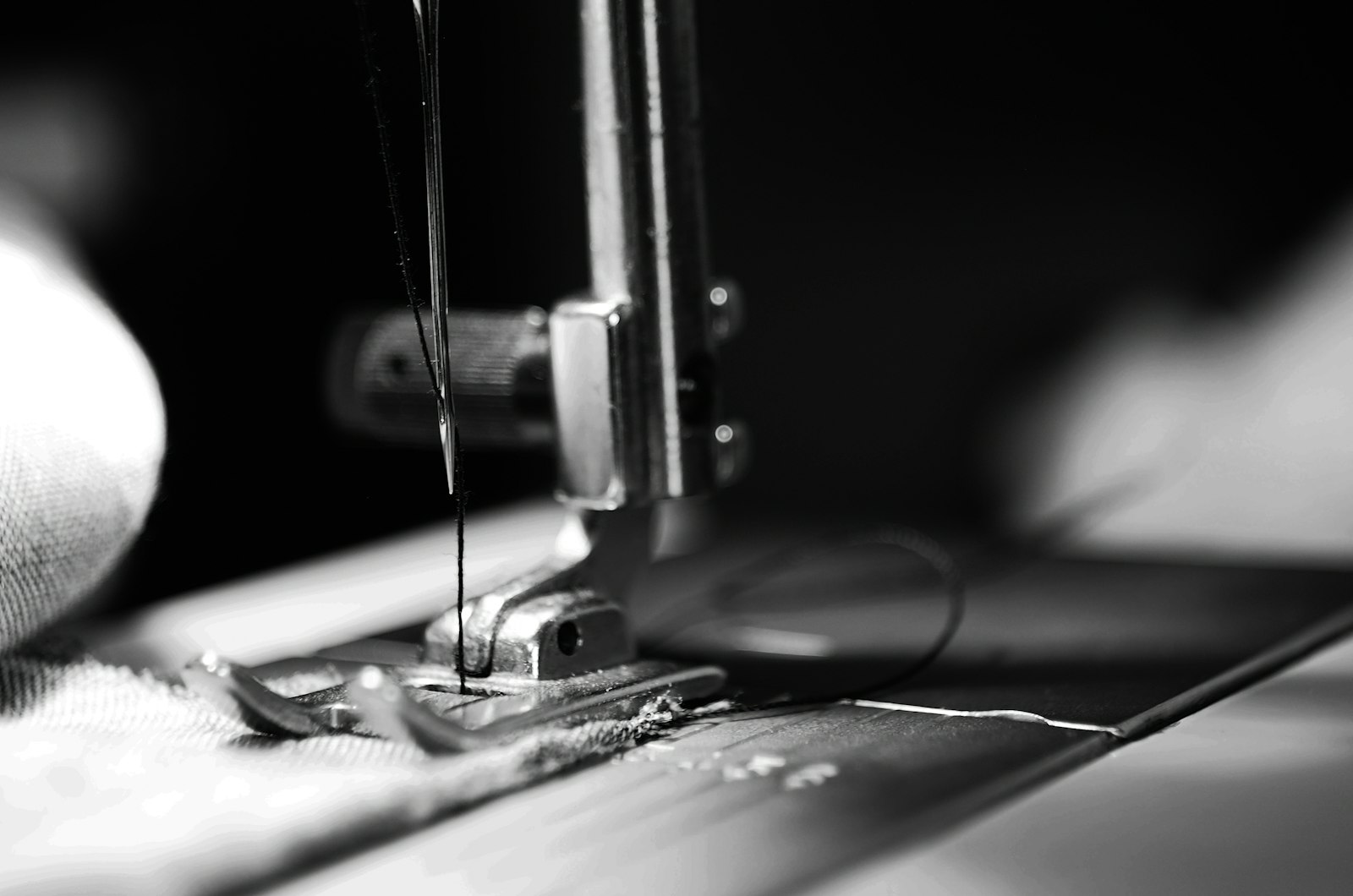 Black and white close-up macro photograph of a sewing machine needle and mechanism